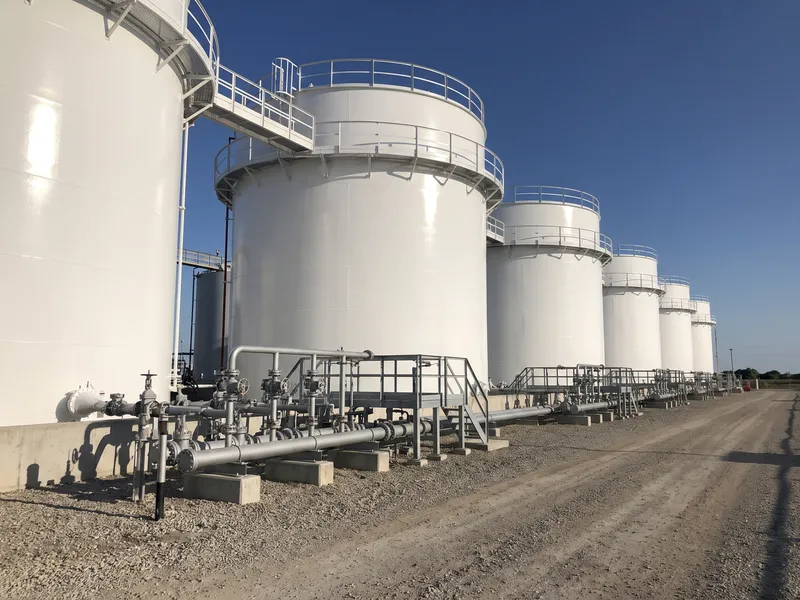 Row of freshly coated white above-ground steel storage tanks in a tank farm