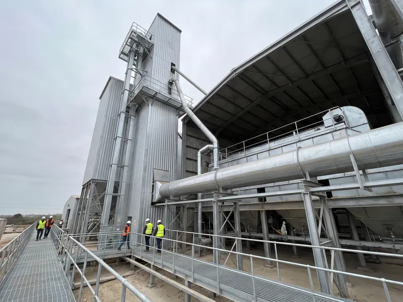 Enclosed bucket elevator and conveyor system rising several stories in a processing plant