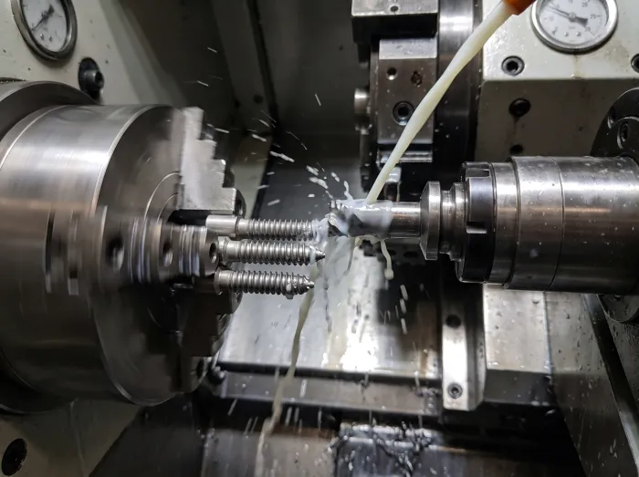 Threaded implant screws being turned on a CNC lathe