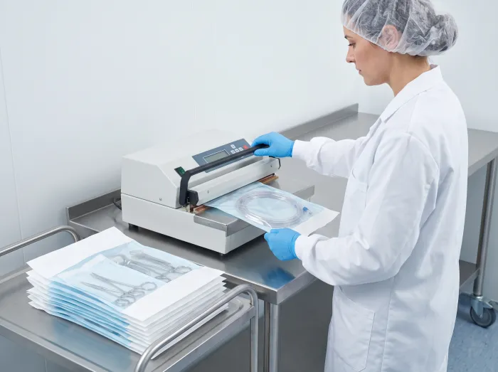 Technician sealing a sterile device pouch on a heat sealer